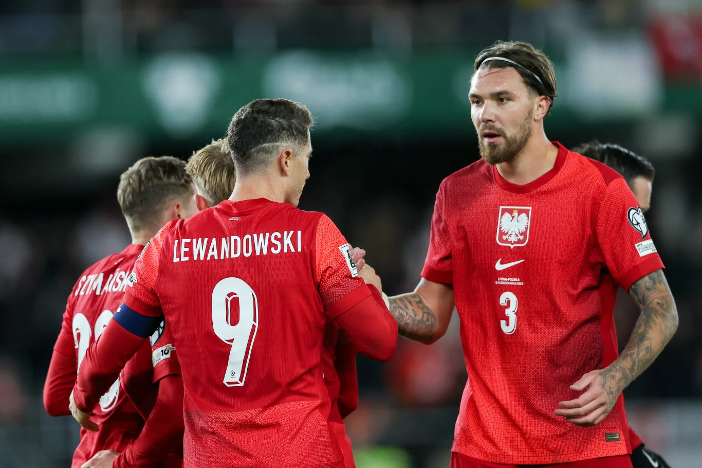 Przemysław Wiśniewski i Robert Lewandowski po meczu Polska - Litwa Polscy piłkarze w czerwonych reprezentacyjnych strojach świętują wspólnie akcję podczas meczu, widoczny napis z nazwiskiem Lewandowski na koszulce z numerem 9.
