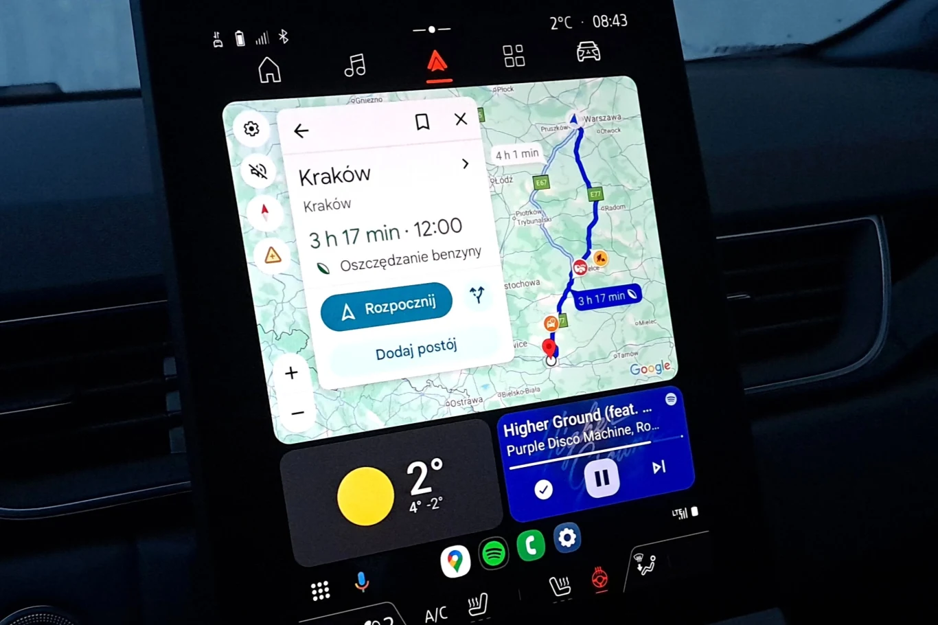 Google Maps z asystentem głosowym Gemini – oto, co się zmieni? Ekran systemu multimedialnego samochodu z włączoną nawigacją Google Maps prowadzącą do Krakowa, pokazujący trasę, pogodę oraz pasek sterowania muzyką.