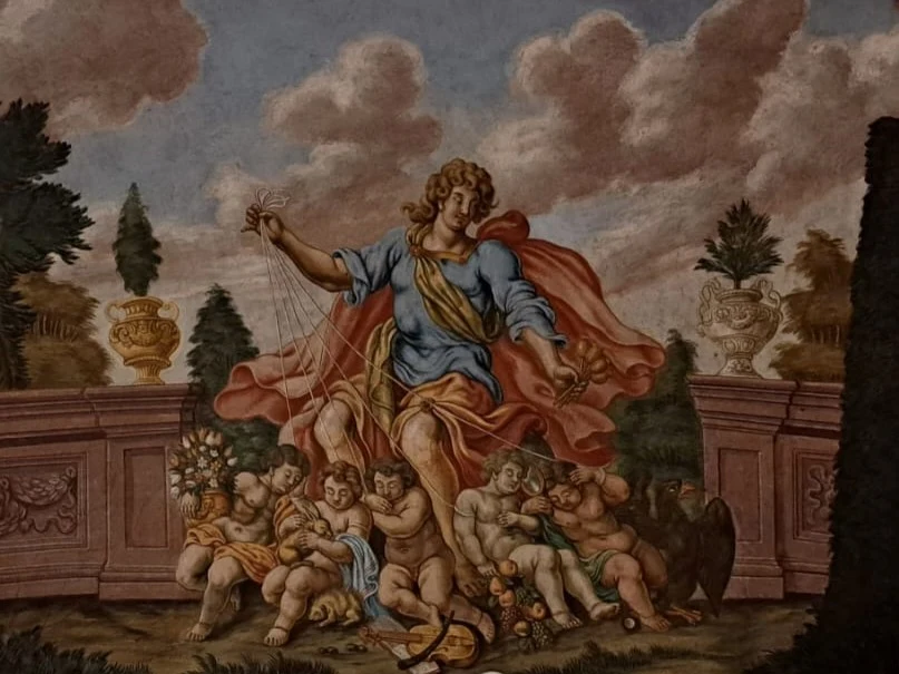 Alegoria pięciu zmysłów na suficie zamku w Nowym Mieście nad Metują Postać w bogato zdobionej szacie, otoczona grupą nagich putt, trzyma w ręce nici przypominające symbole władzy nad losem, w tle znajdują się dekoracyjne wazony, drzewa oraz kamienna balustrada, całość utrzymana w klasycystycznym stylu malarskim.