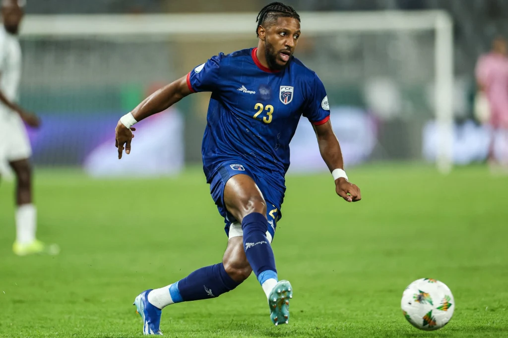 Republika Zielonego Przylądka jedzie na mundial w 2026 roku Piłkarz w niebieskim stroju z numerem 23 kopie piłkę podczas meczu piłkarskiego na stadionie, w tle rozmazana sylwetka przeciwnika i bramka.