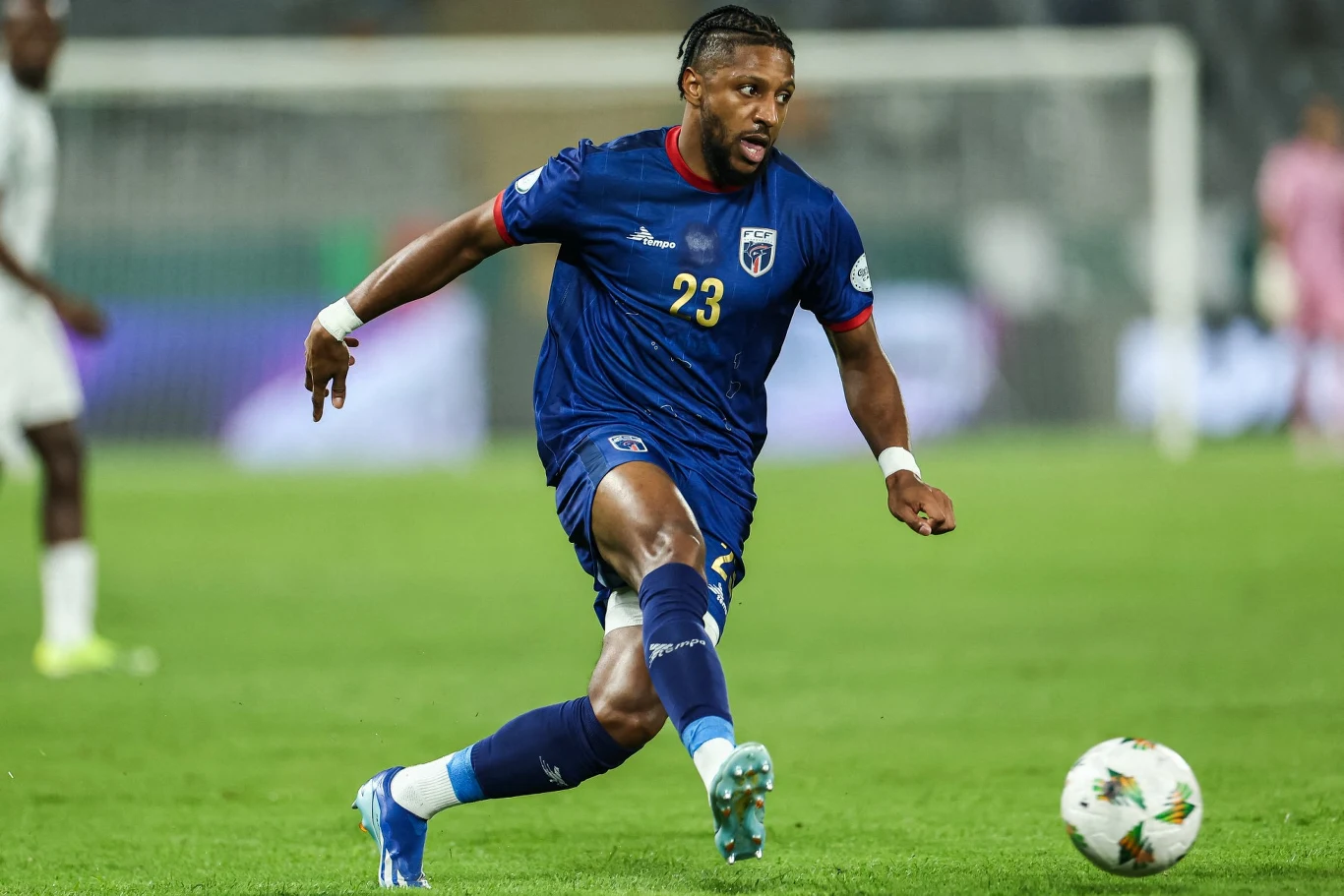 Republika Zielonego Przylądka jedzie na mundial w 2026 roku Piłkarz w niebieskim stroju z numerem 23 kopie piłkę podczas meczu piłkarskiego na stadionie, w tle rozmazana sylwetka przeciwnika i bramka.