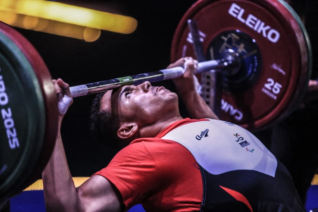 W Kairze trwają mistrzostwa świata w paralimpijskim podnoszeniu ciężarów Sportowiec podczas wyciskania sztangi leżąc, skupiony na wykonaniu ruchu, otoczony ciężarami i profesjonalnym sprzętem siłowym