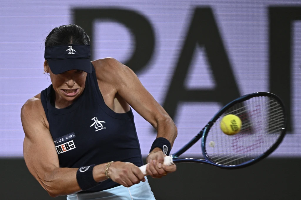 Ajla Tomljanović Dynamiczne ujęcie tenisistki uderzającej piłkę rakietą, wyraz skupienia na twarzy oraz silnie zarysowane mięśnie rąk wskazujące na intensywny wysiłek i zaangażowanie podczas meczu.