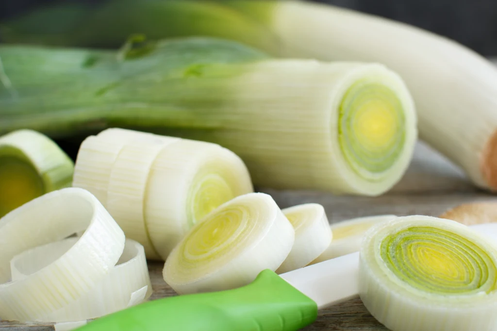 Zdaniem badaczy, pory to jednej z najlepiej wspierających wątrobę warzyw Świeży por pokrojony w plastry leży na desce obok noża z zieloną rączką, w tle widoczna cała łodyga pora.