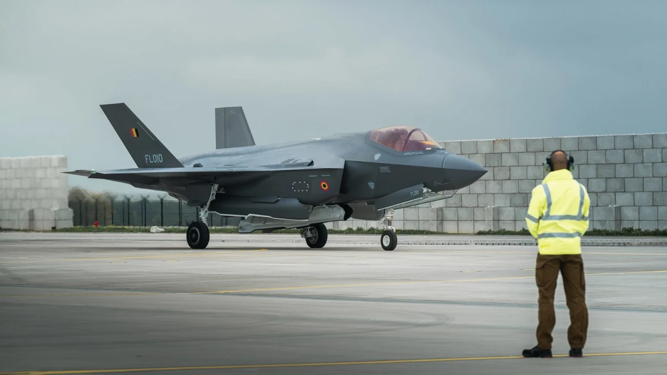 Belgia odebrała pierwsze myśliwce F-35. Na ten moment czekali...Ukraińcy Myśliwiec F-35 na płycie lotniska, przygotowywany do startu lub zakończenia lądowania, w tle pracownik naziemny w kamizelce odblaskowej obserwuje samolot.
