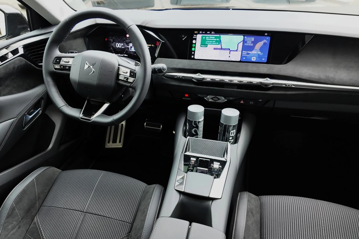 Nowoczesna kabina samochodu z cyfrowym kokpitem, dużym ekranem nawigacji, ergonomiczną kierownicą oraz elegancką konsolą środkową wyposażoną w dwa napoje.