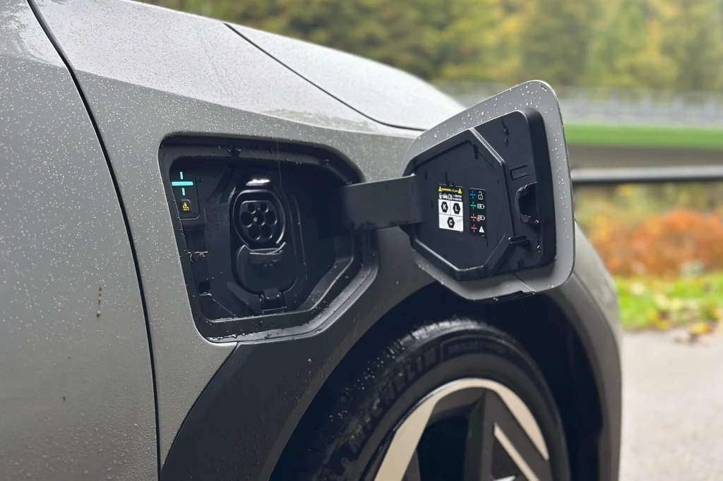 Ładowanie EV4 od 10 do 80 proc. zajmuje około 30 minut. Zbliżenie na port ładowania samochodu elektrycznego z otwartą klapką, widoczne szczegóły konstrukcji i oznaczenia techniczne.