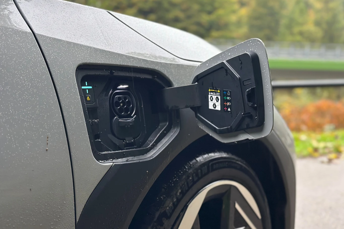 Ładowanie EV4 od 10 do 80 proc. zajmuje około 30 minut. Zbliżenie na port ładowania samochodu elektrycznego z otwartą klapką, widoczne szczegóły konstrukcji i oznaczenia techniczne.