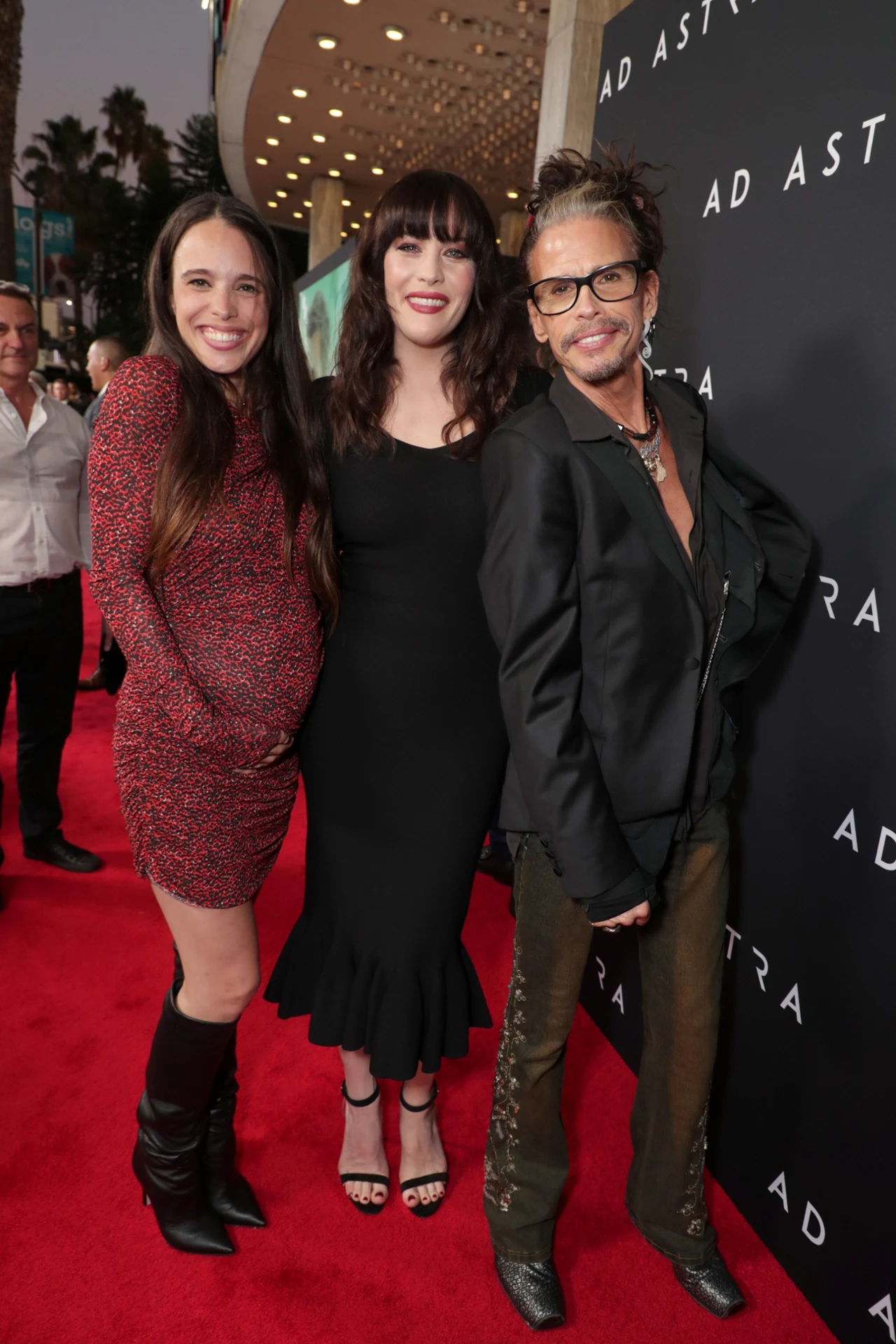 Steven Tyler i jego dwie córki: Chelsea i Liv - Los Angeles, 18 września 2019 r. Trzy osoby pozujące razem na czerwonym dywanie podczas wydarzenia filmowego, w tle ścianka z napisem Ad Astra, eleganckie stroje i wyraziste oświetlenie eventu.