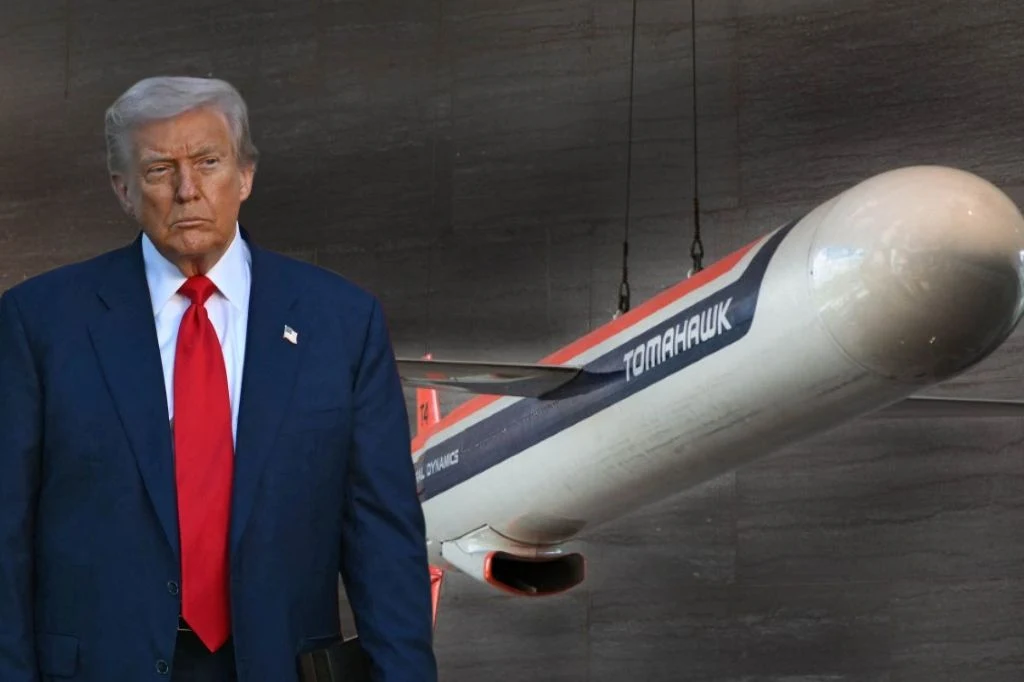 Starszy mężczyzna w garniturze i czerwonym krawacie stoi na tle dużego pocisku manewrującego z napisem Tomahawk, eksponowanego w muzealnych warunkach.