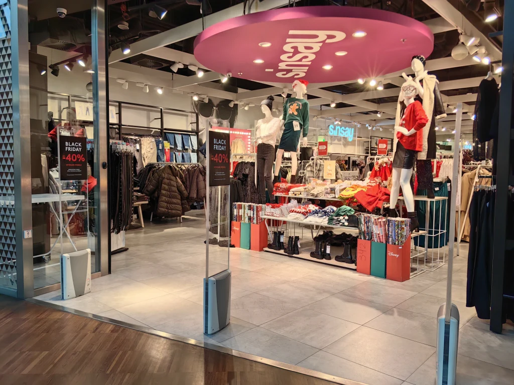 Sinsay otwiera kolejne sklepy w Ukrainie Wnętrze sklepu odzieżowego z manekinami ubranymi w jesienne i zimowe ubrania, półki i stojaki z ubraniami, promocje Black Friday oraz widoczne oznaczenie marki Sinsay.