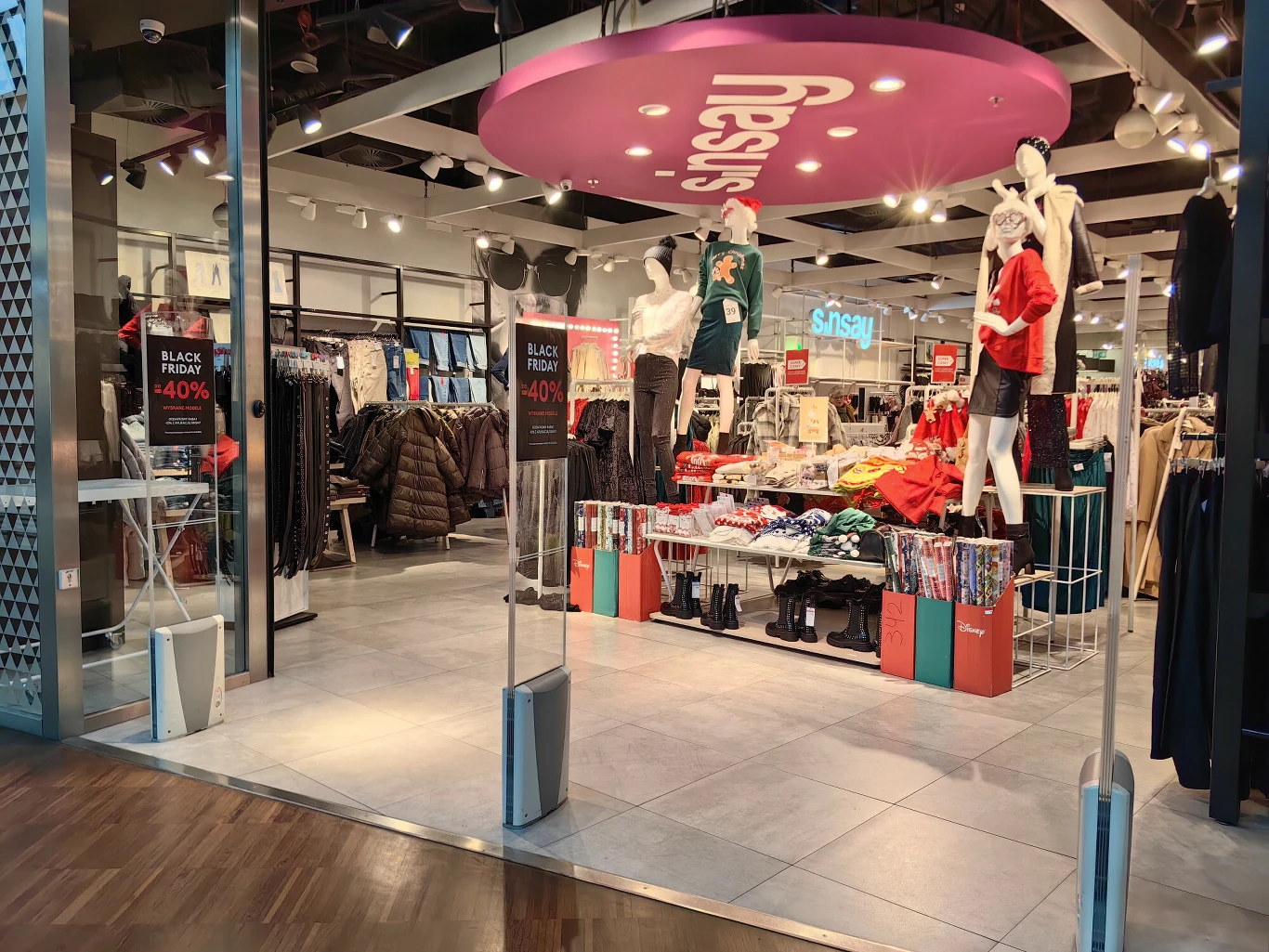 Sinsay otwiera kolejne sklepy w Ukrainie Wnętrze sklepu odzieżowego z manekinami ubranymi w jesienne i zimowe ubrania, półki i stojaki z ubraniami, promocje Black Friday oraz widoczne oznaczenie marki Sinsay.