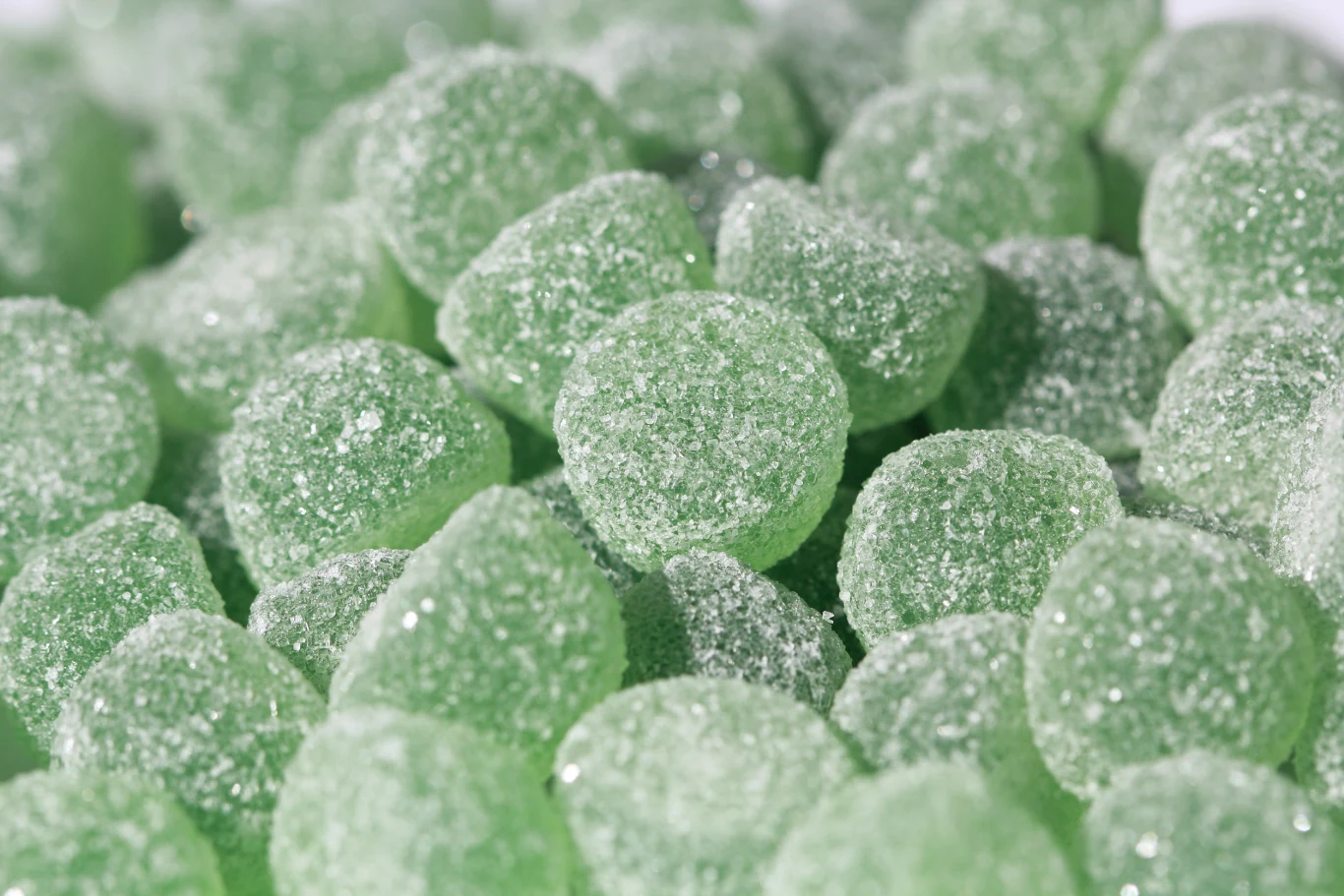 Miętówki nie tylko odświeżają oddech. Poprawiają też samopoczucie podczas przeziębienia Zielone żelki o zaokrąglonych kształtach pokryte warstwą cukru, tworzące apetyczną, słodką kompozycję.