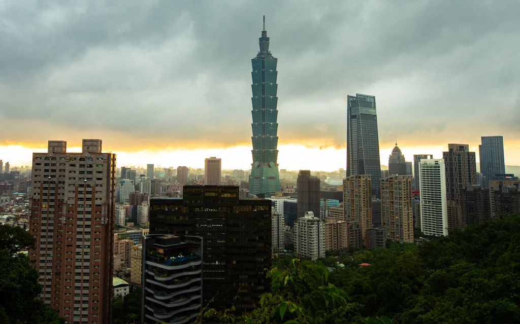 Tajpej - stolica Tajwanu, uważanego za jednego z "azjatyckich tygrysów" Panorama miejskiego krajobrazu z dominującym wieżowcem Taipei 101 pośród innych wysokich budynków, pod pochmurnym niebem.