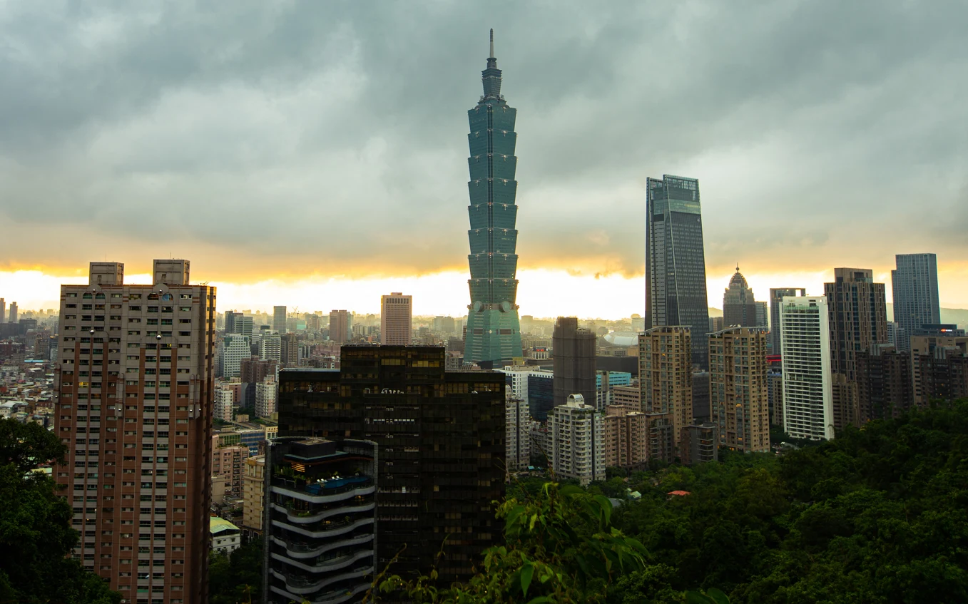 Tajpej - stolica Tajwanu, uważanego za jednego z "azjatyckich tygrysów" Panorama miejskiego krajobrazu z dominującym wieżowcem Taipei 101 pośród innych wysokich budynków, pod pochmurnym niebem.