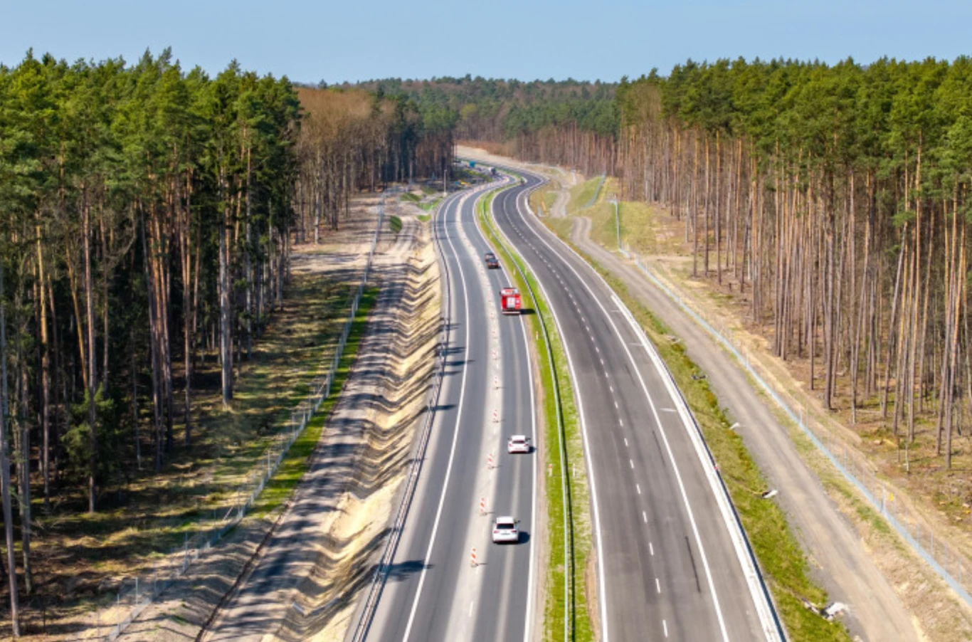 Czy kierowcy wreszcie przejadą z Czech nad Bałtyk bez zatrzymywania się na granicy? Dwupasmowa droga szybkiego ruchu biegnąca przez las, kilka samochodów jadących w obu kierunkach, po bokach rzędy wysokich drzew sosnowych i rzadziej porośnięte skarpy, bez innych obiektów i ludzi.
