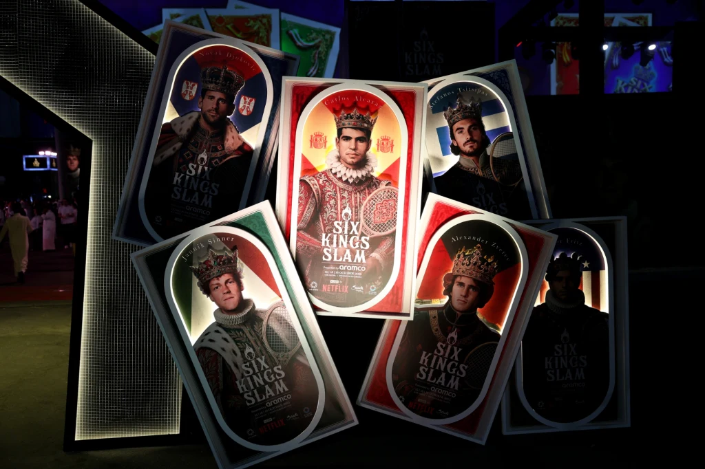 Turniej Six Kings Slam Plakaty przedstawiają pięciu mężczyzn ubranych w korony i stroje królewskie, stylizowane na karty do gry, z napisem Six Kings Slam, na środku plakat z wyróżniającym się czerwonym tłem.