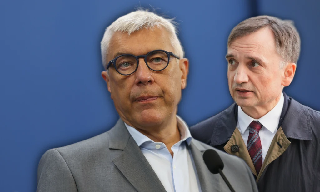 Dwóch mężczyzn w garniturach stoi na tle jednolitego niebieskiego tła, jeden z nich ma mikrofon przed sobą, co sugeruje sytuację oficjalną lub konferencję prasową.