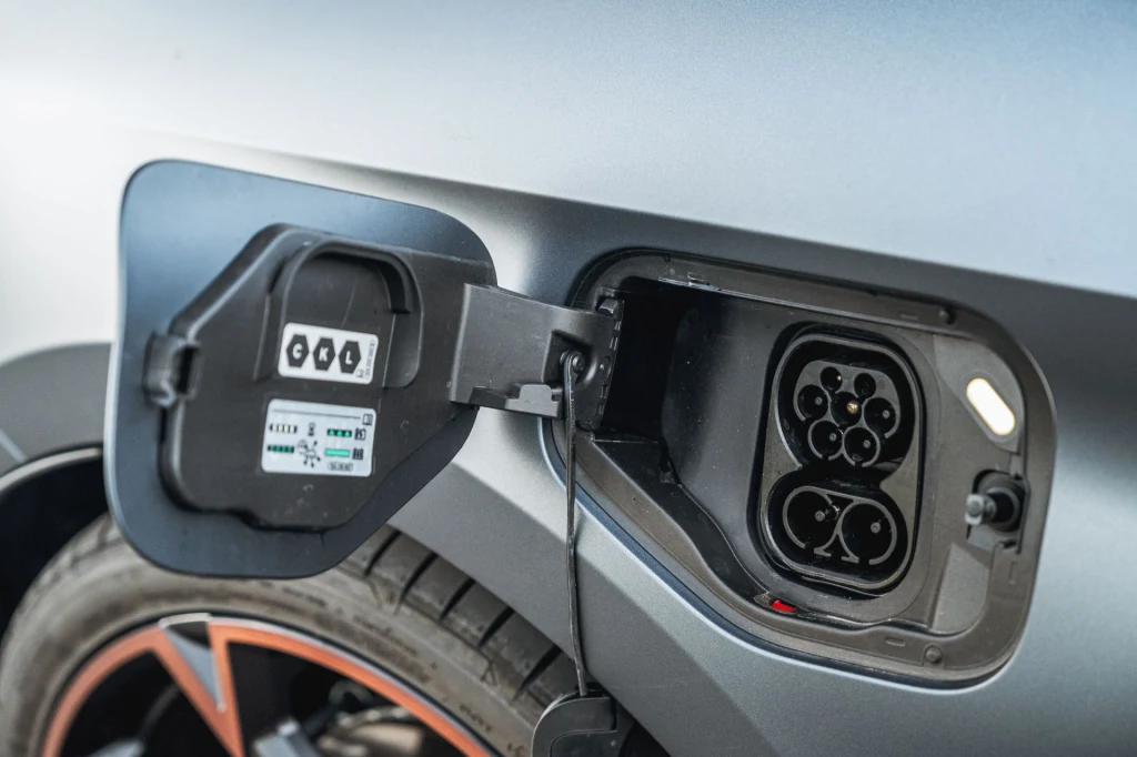 Akumulator o pojemności netto 19,7 kWh można ładować prądem stałym o mocy 50 kW. Wtyczka do ładowania samochodu elektrycznego znajdująca się w otwartym gnieździe ładowania na nadkolu pojazdu, widoczna część koła i charakterystyczna konstrukcja panelu.