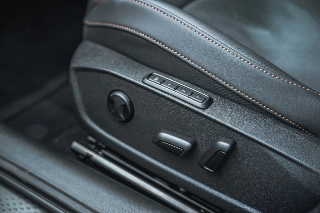 Cupra Leon z 204-konną hybrydą może być opcjonalnie wyposażona w elektrycznie regulowany fotel kierowcy z pamięcią ustawień. Panel regulacji elektrycznej fotela samochodowego z widocznymi przyciskami i przeszyciem na skórzanej tapicerce.