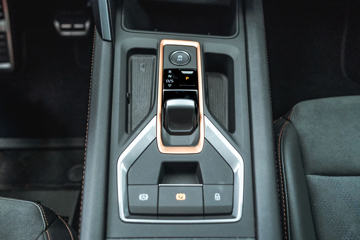 Hybryda plug-in współpracuje z sześciobiegową skrzynią dwusprzęgłową, którą obsługujemy za pomocą stosunkowo niewielkiej dźwigni. Ale auto wyposażone jest również w łopatki zmiany biegów znajdujące się na kolumnie kierownicy. Konsola centralna samochodu z nowoczesną dźwignią zmiany biegów, otoczona eleganckim wykończeniem i przyciskami elektronicznego hamulca ręcznego oraz funkcji parkowania, elementy wnętrza utrzymane w czarnej kolorystyce z detalami w kolorze miedzi.