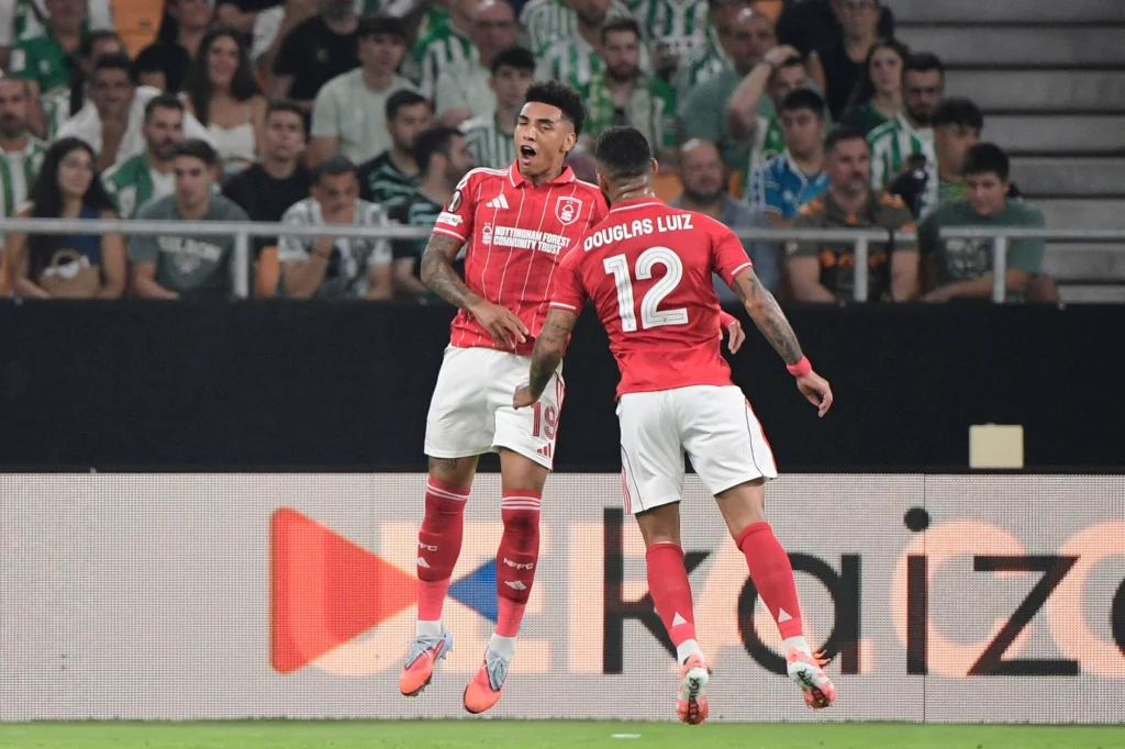 Piłkarze Nottingham Forest w tym sezonie nie mają zbyt wielu okazji do radości Dwóch piłkarzy drużyny w czerwonych strojach świętuje zdobycie gola na tle trybun wypełnionych kibicami, wokół widoczne są elementy stadionu i reklamy.