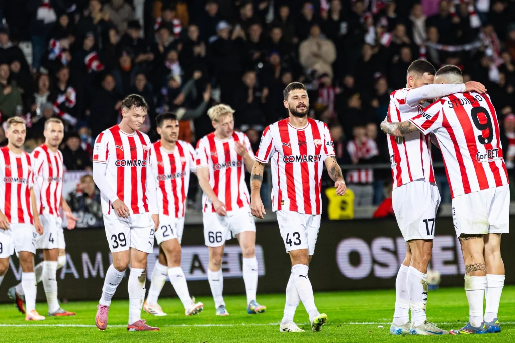 Cracovia była zdecydowanie lepsza od Rakowa Częstochowa w spotkaniu 12. kolejki PKO Ekstraklasy Drużyna piłkarska ubrana w biało-czerwone koszulki w paski na boisku, kilku zawodników świętuje, reszta spaceruje po murawie, w tle kibice na trybunach.
