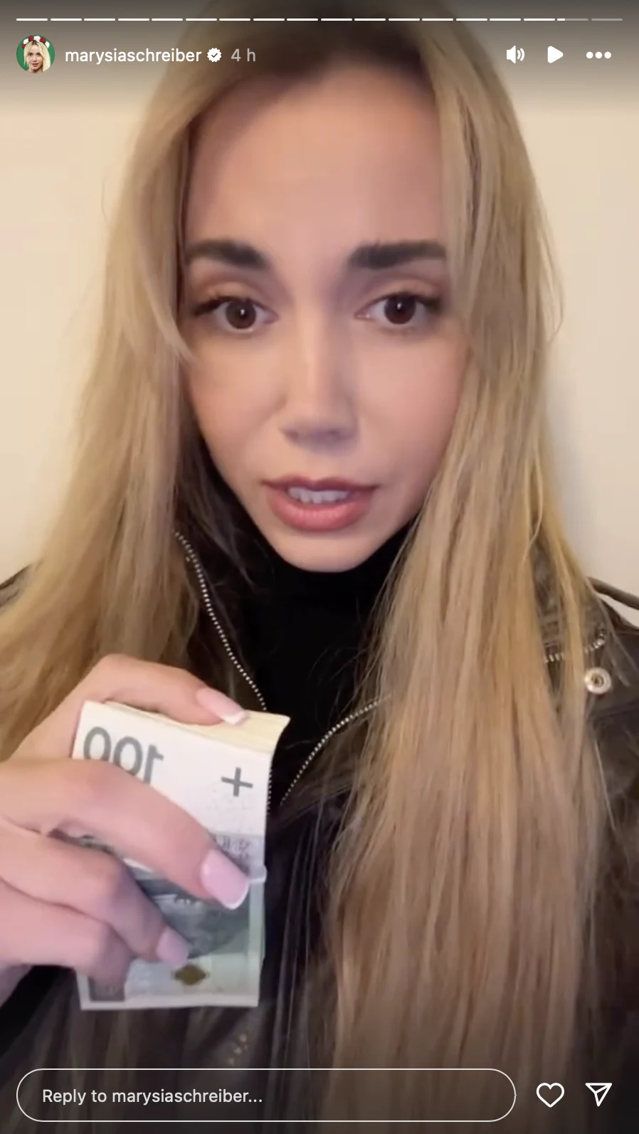 Marianna Schreiber pokazała wypłatę za ostatnią walkę Młoda kobieta o długich blond włosach trzyma w dłoni banknot o nominale 100 euro, patrzy prosto w obiektyw, ubrana w czarną kurtkę, z jasnym tłem w tle.