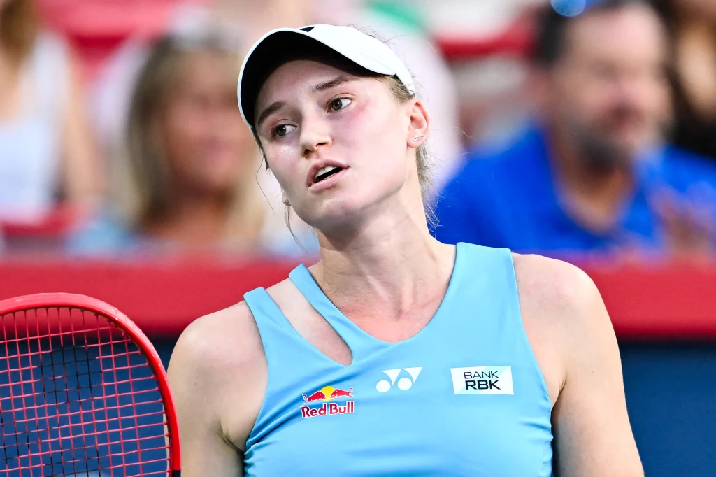 Jelena Rybakina Tenisistka w sportowej koszulce i czapce podczas meczu, widoczna rakieta tenisowa, tło rozmyte pokazujące publiczność