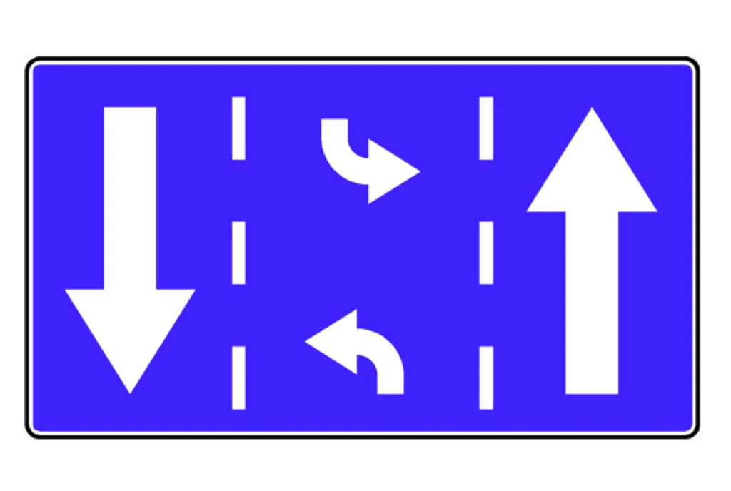 Znak F-23 wprowadza "środkowy pas wielofunkcyjny" Tablica drogowa z niebieskim tłem i białymi strzałkami wskazującymi kierunki ruchu na poszczególnych pasach: lewy pas do jazdy w lewo, środkowy do skrętu w lewo lub jazdy prosto, prawy pas do jazdy wyłącznie na wprost.