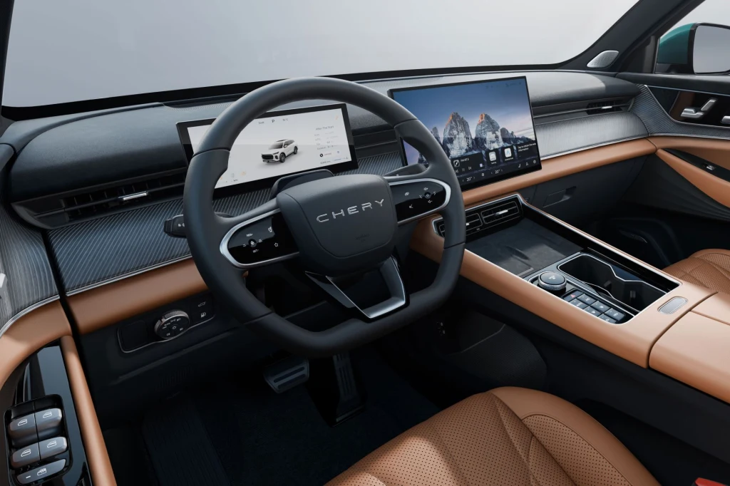 Chery Tiggo 9 wyposażony jest w 10,25-calowy zestaw wskaźników oraz 15,6-calowy wyświetlacz multimediów. Nowoczesne wnętrze samochodu marki Chery z cyfrowym kokpitem, dwoma dużymi ekranami na desce rozdzielczej, kierownicą z logo producenta oraz brązową skórzaną tapicerką siedzeń i wykończenia.