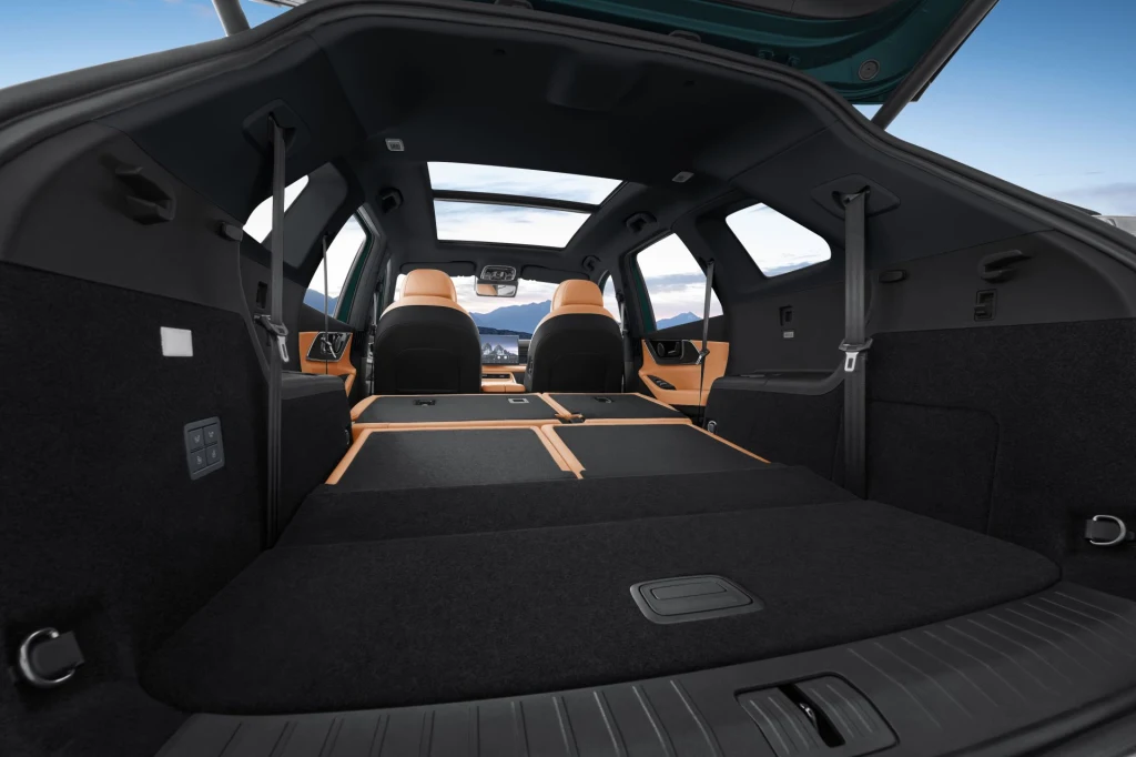 Po złożeniu drugiego i trzeciego rzędu foteli bagażnik Chery Tiggo 9 pomieści 2 065 litrów. Widok na bardzo przestronny bagażnik samochodu typu SUV z rozłożonymi oparciami tylnych siedzeń, co daje dużą i płaską powierzchnię załadunkową, a w tle widoczne są dwa przednie siedzenia w jasnej tapicerce.