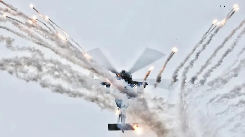 Z-20T to chińska odpowiedź na śmigłowiec wojskowy Black Hawk. Helikopter bojowy w trakcie wystrzeliwania flar przeciwrakietowych, intensywne smugi dymu i jaskrawe światła flar kontrastują z jasnym, jednolitym tłem nieba.