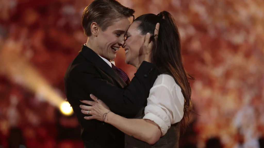 Katarzyna Zillmann i Janja Lesar Dwie osoby obejmujące się, patrzące sobie w oczy z radością na tle rozświetlonego, ciepłego tła, gest bliskości i uczucia.