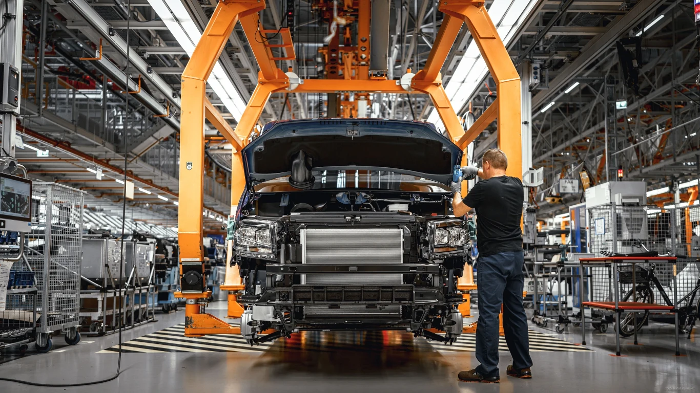 Nowa generacja Volkswagena Crafter będzie produkowana w Polsce Pracownik kontroluje montaż samochodu na linii produkcyjnej w nowoczesnej fabryce, wokół widoczne są elementy technologii i infrastruktury przemysłowej.