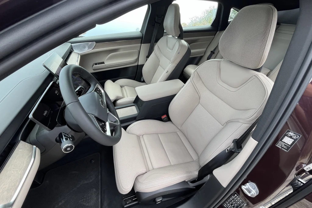 Luksusowe wnętrze samochodu z jasną tapicerką, nowoczesną deską rozdzielczą oraz wielofunkcyjną kierownicą, wykończenia podkreślają komfort i elegancję pojazdu.