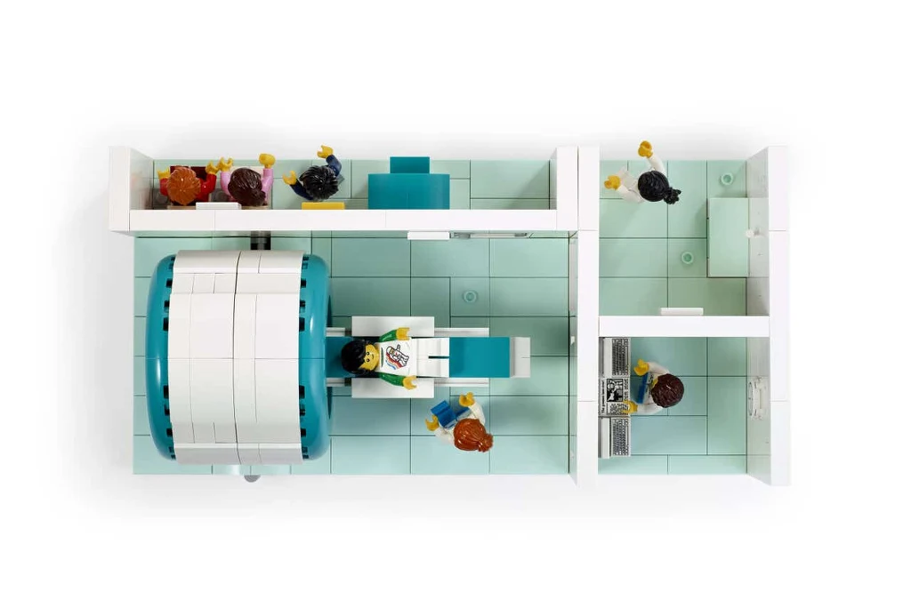 Zestaw LEGO MRI Scanner składa się z czterech pomieszczeń: korytarza dla oczekujących, salki przygotowań, gainetu techników i głównego pokoju z urządzeniem MRI Szpitalny pokój z zabawkowych klocków, w którym pacjent przechodzi badanie przy użyciu tomografu komputerowego, wokół znajdują się figurki personelu medycznego i pacjentów.