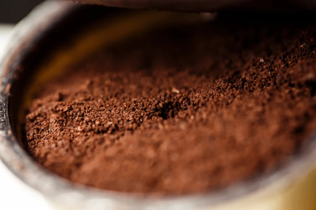 Mielona kawa w lodówce szybko neutralizuje nieprzyjemne zapachy Świeżo zmielona kawa o drobnej, równomiernej konsystencji, ukazująca strukturę i intensywny kolor zmielonych ziaren w otwartym pojemniku.