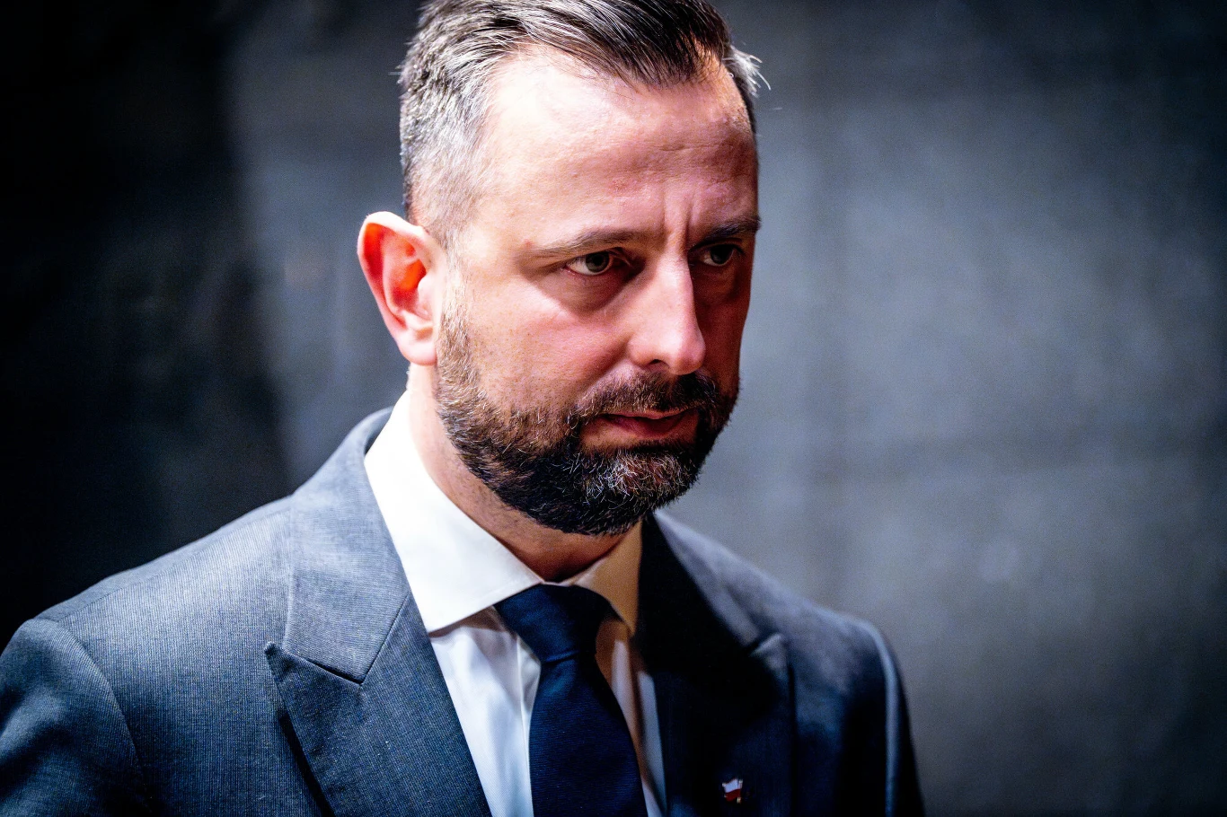 Wicepremier Władysław Kosiniak-Kamysz wkrótce ponownie stanie do walki o fotel lidera PSL Mężczyzna w średnim wieku w granatowym garniturze i białej koszuli z niebieskim krawatem, stojący na ciemnym tle, z poważnym wyrazem twarzy oraz krótkimi włosami i zadbaną brodą.