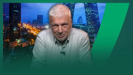 Starszy mężczyzna o siwych włosach w jasnej koszuli patrzy bezpośrednio na obserwatora, w tle rozświetlone wieżowce oraz nocna panorama miasta.