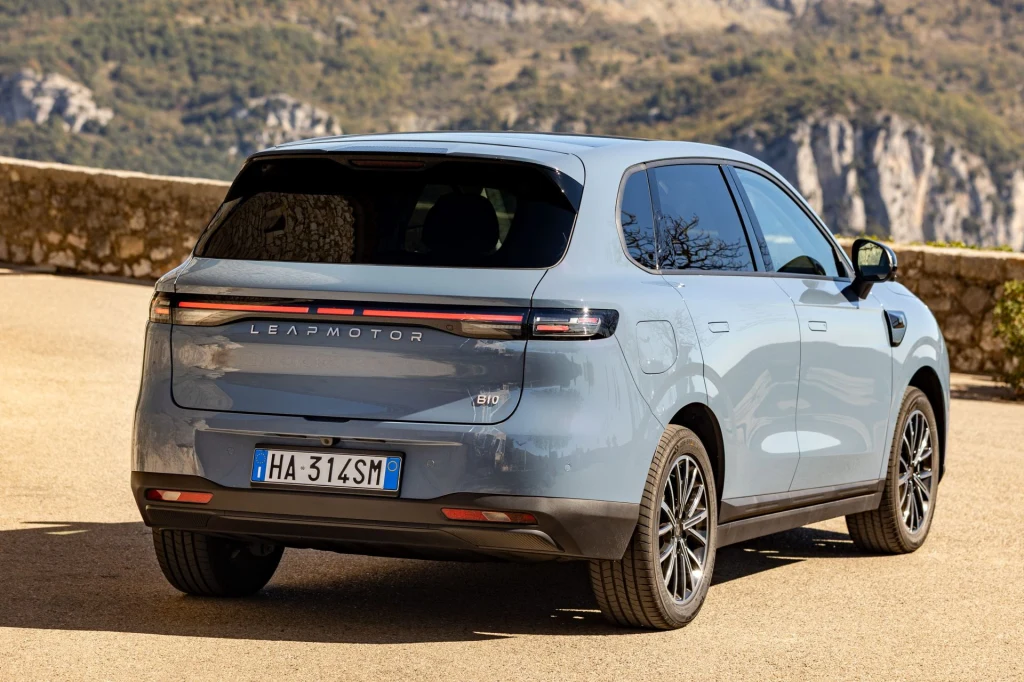 Srebrnoszary samochód osobowy typu SUV marki Leapmotor stoi zaparkowany na drodze asfaltowej, w tle widoczne są górskie skały i zielona roślinność.