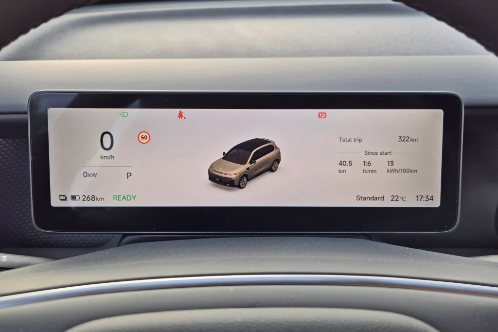 Leapmotor B10 potrafi zaskoczyć zużyciem energii - wynik na poziomie 13 kWh/100 km można uzyskać bez silenia się na ecodriving Cyfrowy wyświetlacz deski rozdzielczej samochodu elektrycznego z wizualizacją pojazdu pośrodku oraz informacjami o prędkości, przebiegu, zużyciu energii i temperaturze.