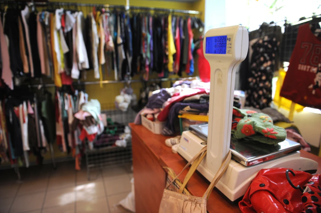 To, co pokazała waga determinowało, czy daną rzecz kupimy, czy nie Stos ubrań na wadze elektronicznej ustawionej na ladzie, w tle widoczne wieszaki z różnorodną odzieżą używaną zawieszoną na metalowych kratkach oraz jasne wnętrze sklepu