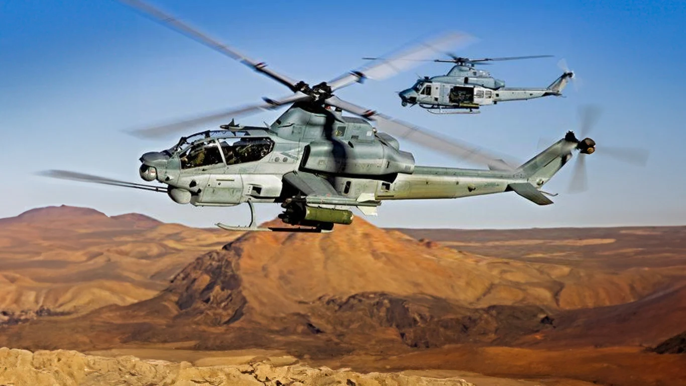 Stany Zjednoczone gotowe dostarczyć Ukrainie śmigłowce Viper i Venom Dwa wojskowe śmigłowce bojowe lecą nad pustynnym, górzystym terenem przy błękitnym niebie, pierwsza maszyna dominuje ujęcie z wyraźnie widocznymi szczegółami kadłuba i uzbrojenia.