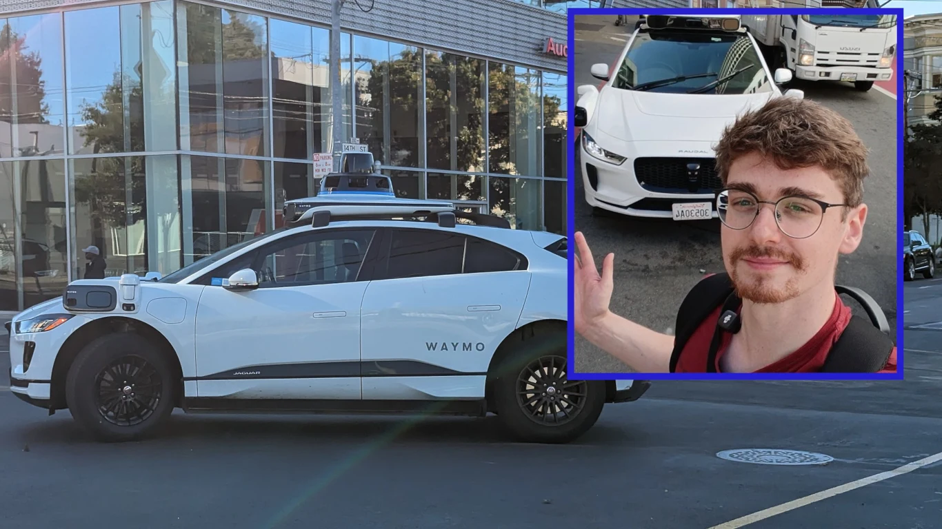 Jechałem autonomiczną taksówką po ulicach San Francisco. Nasuwa mi się tylko jeden wniosek Samochód autonomiczny marki Waymo zaparkowany przy ulicy przed nowoczesnym budynkiem z przeszkloną fasadą, z wyraźnie widocznymi sensorami na dachu oraz mężczyzna pozujący na tle identycznego samochodu, uśmiechnięty w kadrze.