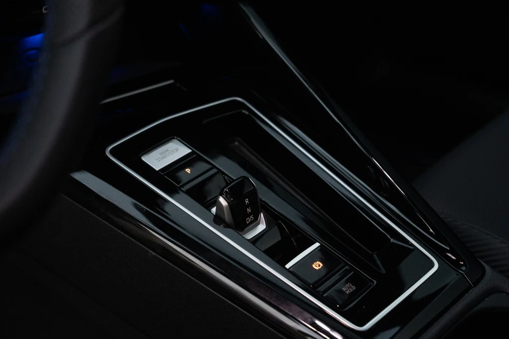 Tak jak w zwykłym Golfie - również w "eRce" wybierak dwusprzęgłowej przekładni ma formę stosunkowo niedużego przełącznika Nowoczesna konsola środkowa samochodu z elektroniczną dźwignią zmiany biegów, przyciskiem hamulca postojowego i eleganckim, czarnym wykończeniem.