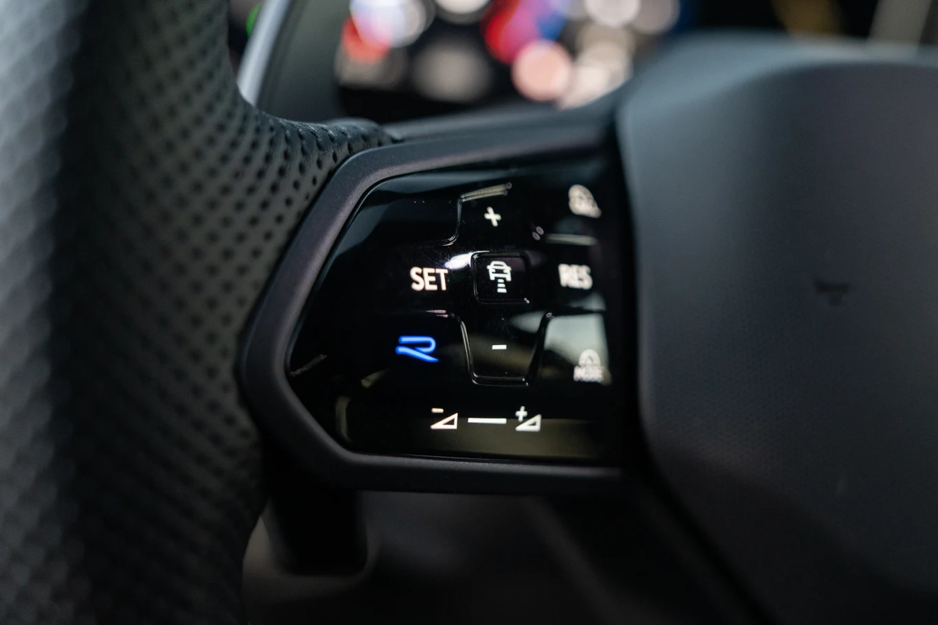 Volkswagen Golf R Black Edition Panel sterowania na kierownicy samochodu z widocznymi przyciskami do regulacji tempomatu oraz innych systemów wspomagających jazdę, z wyraźnymi symbolami, w tym litera R podświetlona na niebiesko.