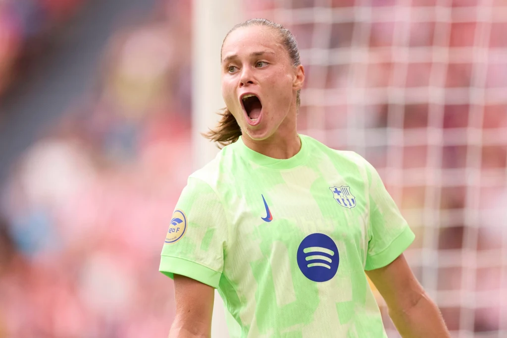 Ewa Pajor Piłkarka w jasnozielonej koszulce drużyny FC Barcelona z otwartymi ustami wyrażająca emocje, w tle widoczna siatka bramki stadionowej.