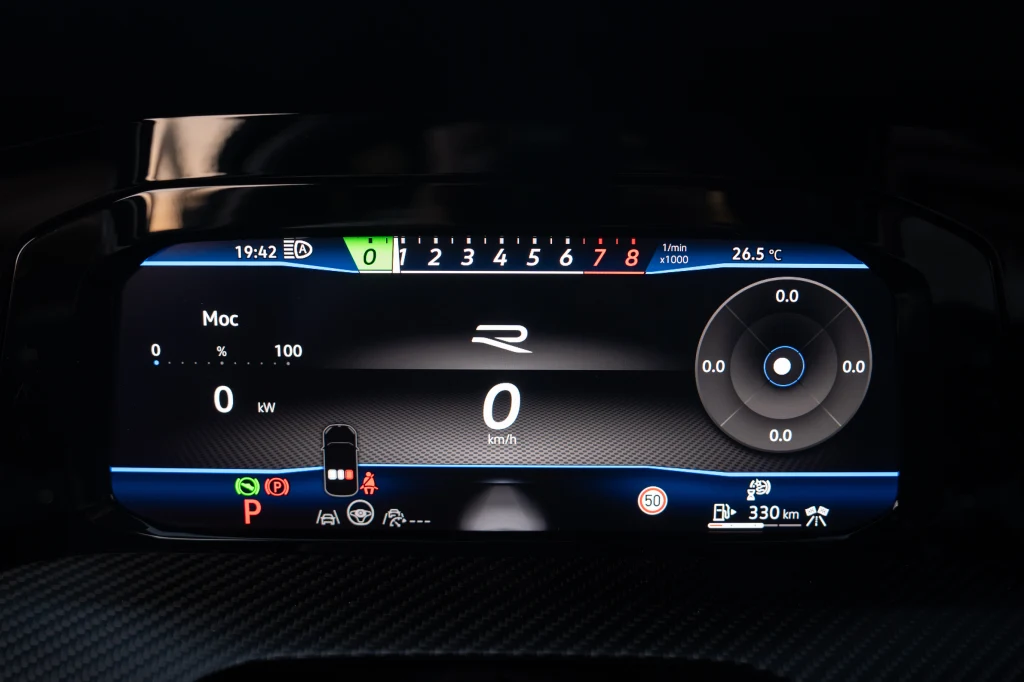 Sposób prezentowania wskazań na ekranie wskaźników zależy od wybranego trybu jazdy. Na zdjęciu widok w trybie Race Cyfrowy zestaw wskaźników samochodu wyświetlający aktualną prędkość, poziom mocy, temperaturę, wskazania nawigacji oraz liczne kontrolki i informacje o stanie pojazdu.