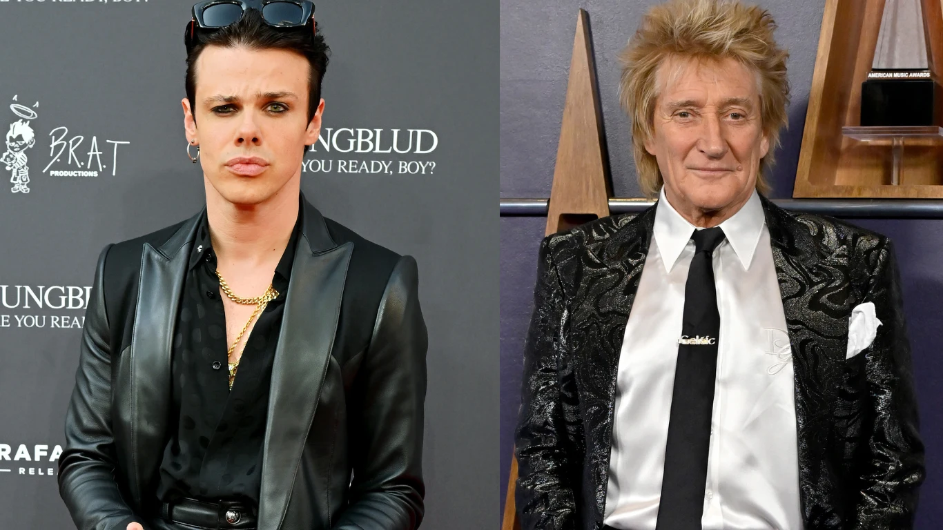 Yungblud, Rod Stewart Dwóch mężczyzn w eleganckich stylizacjach stojących na tle ścianki oraz ściany z elementami dekoracyjnymi, jeden z nich ubrany w czarną skórzaną kurtkę i ciemne okulary na głowie, drugi w wzorzystą marynarkę z białą koszulą i czarnym krawatem.